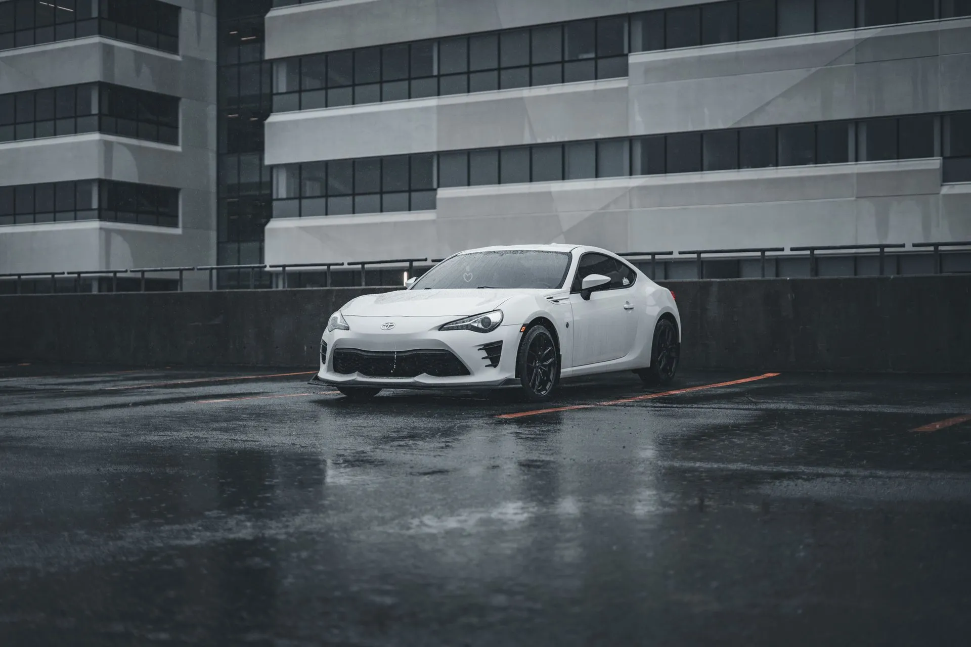 White coupe parked in the rain outside the shop